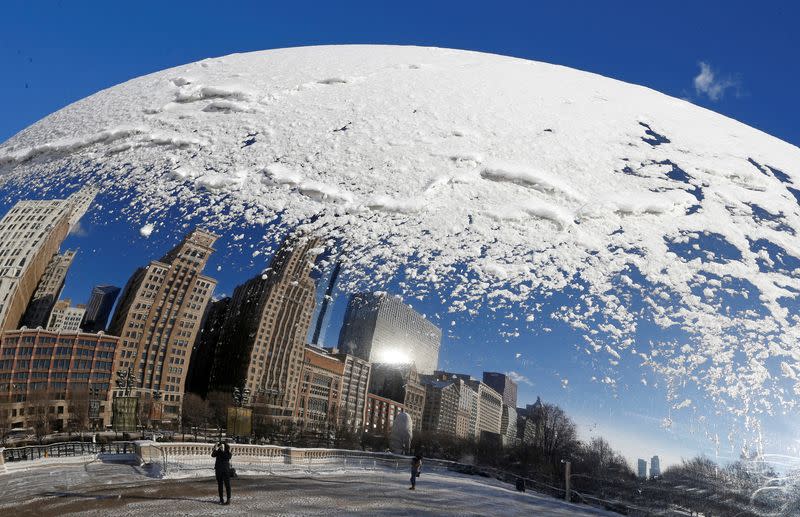 FILE PHOTO: A woman and the Chicago skyline are reflected in the snow covered, curved surface of the "Cloud Gate" sculpture in Chicago