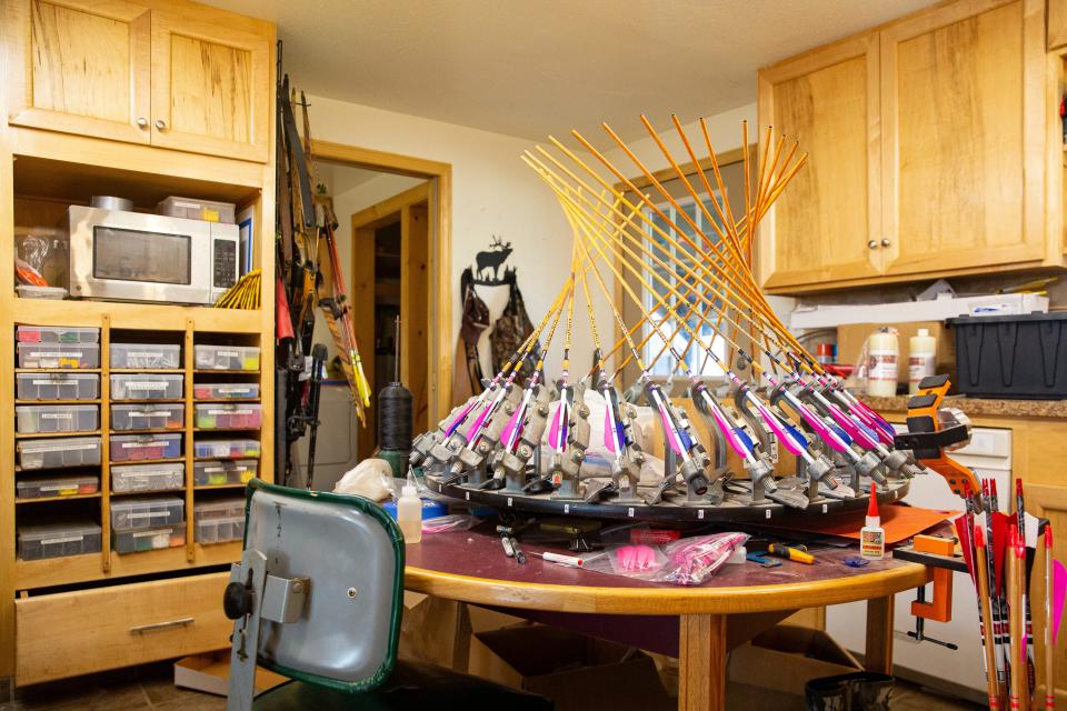 Andy Ponce uses a fletching station to help place turkey feathers onto the arrows.