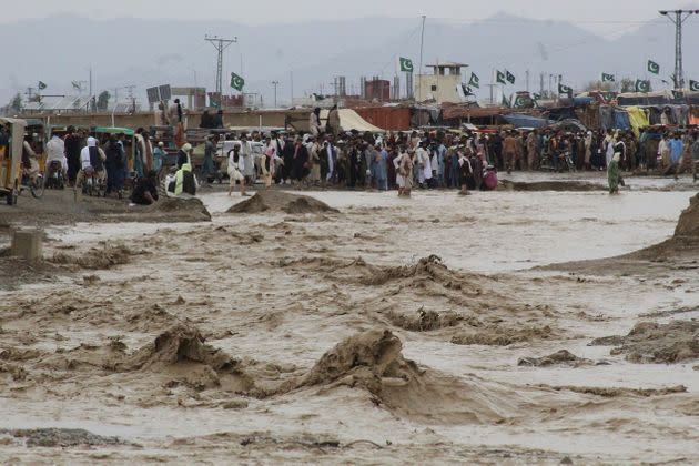 People wade through flooded mud water after heavy monsoon rainfall in the border town of Chaman in Balochistan province on Aug. 25, 2022. (Photo: ABDUL BASIT/AFP/Getty Images)