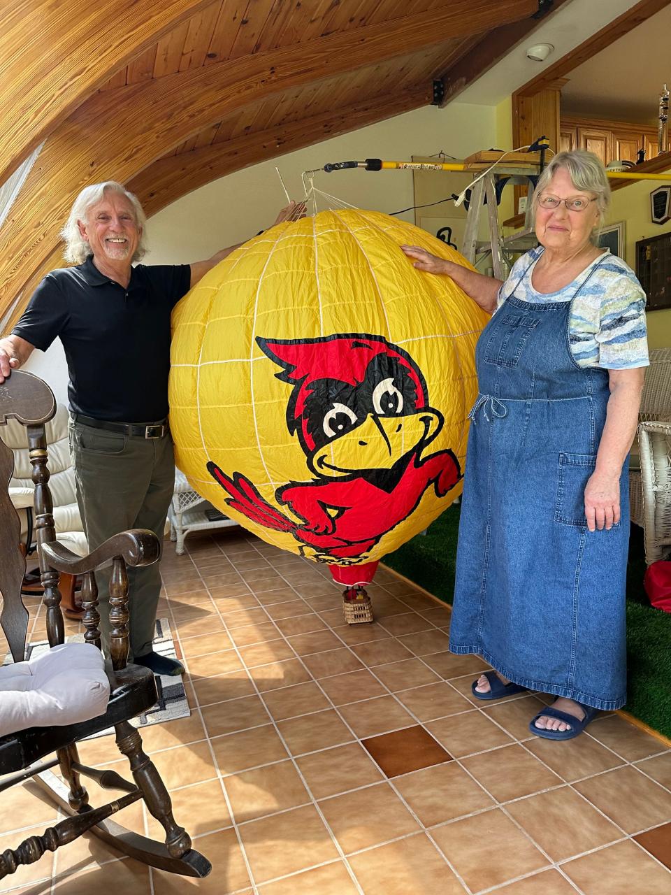 Bill and Toni Woodman pose in the conservatory of their home with a model of their home "Cy in the air" balloon.