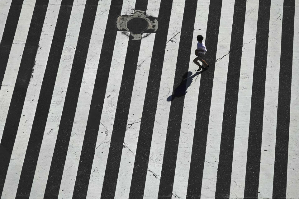 A woman runs across the famous Shibuya crossing Thursday, June 13, 2019, in Tokyo. It's not just a crossing. Located just outside Shibuya Station, the scramble crossing is one of the top tourist attractions in Japan. It's so famous that there's an observation deck on the rooftop of a building built to watch the crossing. During rush hours, an estimated 1000 to 2500 people cross the intersection during each traffic light change. (AP Photo/Jae C. Hong)