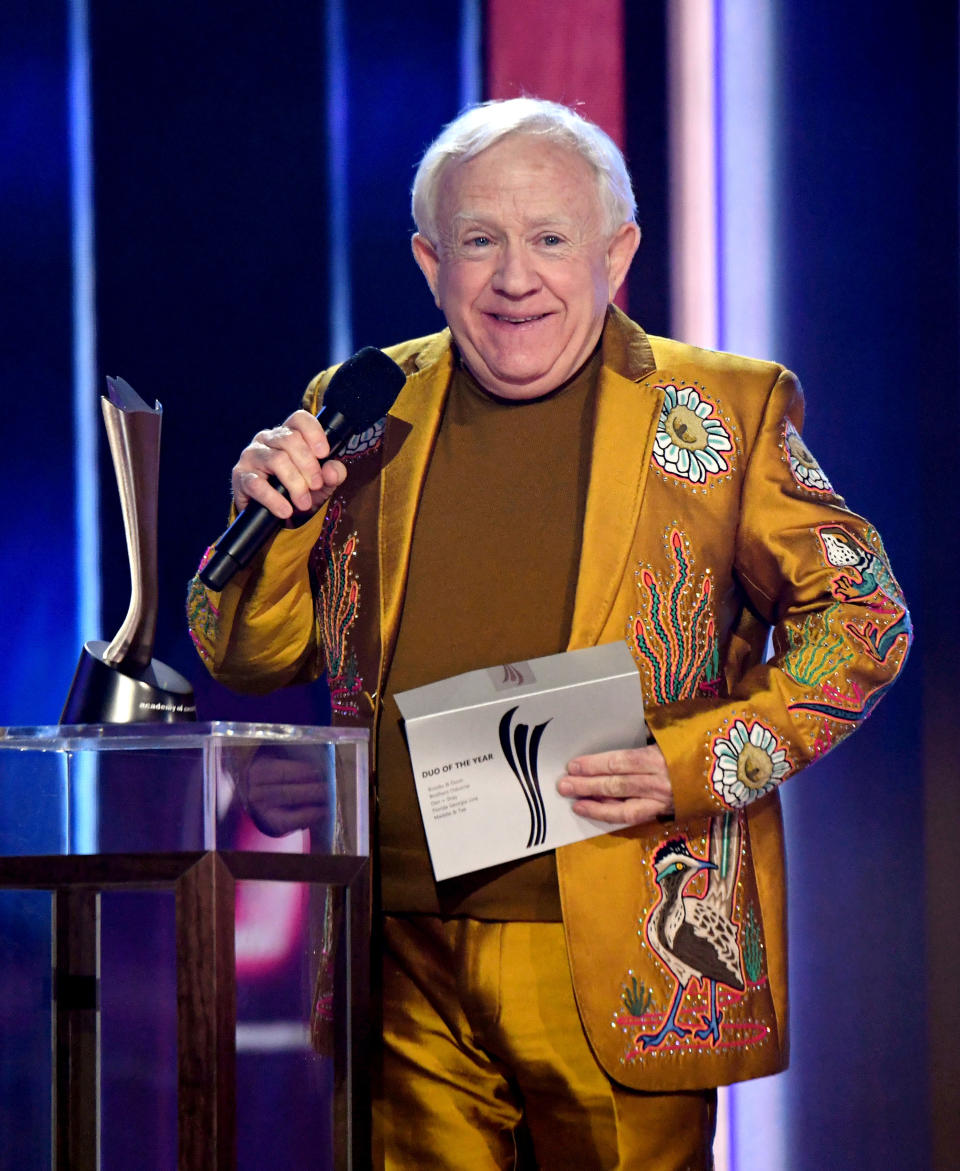 Leslie in a shiny embroidered suit with matching shirt while presenting an award