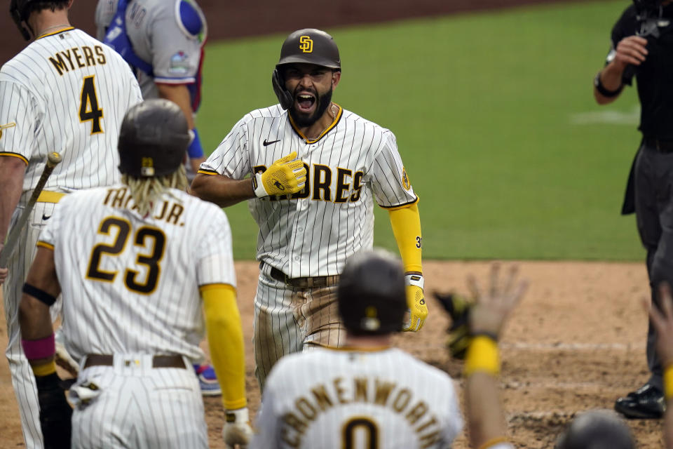 San Diego Padres' Eric Hosmer, center, reacts with teammates after hitting a grand slam during the fifth inning of a baseball game against the Texas Rangers, Thursday, Aug. 20, 2020, in San Diego. (AP Photo/Gregory Bull)