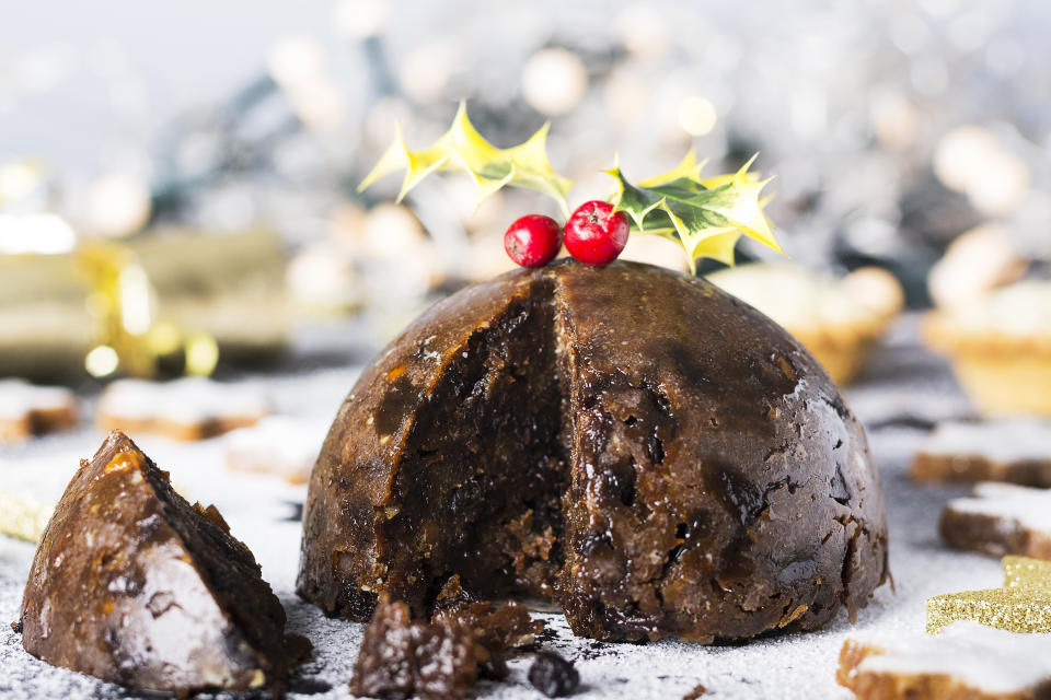 Christmas Pudding, mince pies and Christmas cookies. Christmas scene and decorations in the background.