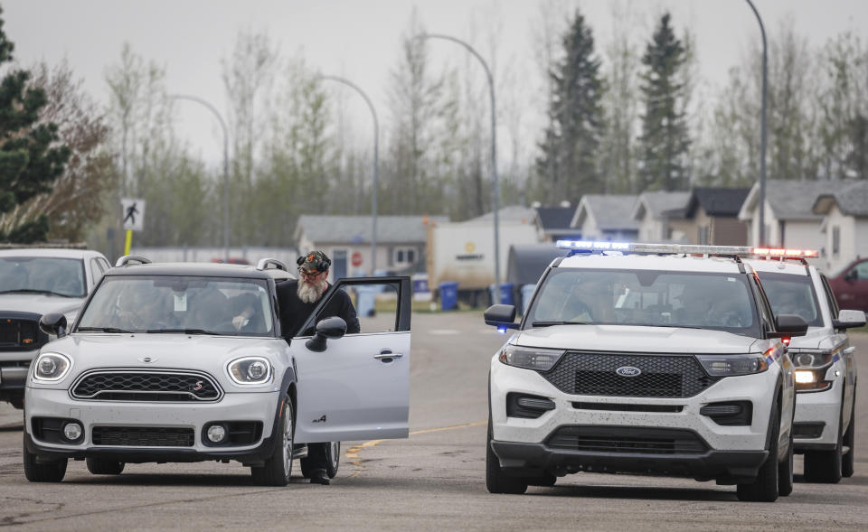 A resident gets back into his vehicle after speaking with police officers blocking the entrance to the evacuated neighborhood of Prairie Creek in Fort McMurray, Alberta, on Wednesday, May 15, 2024. (Jeff McIntosh/The Canadian Press via AP)