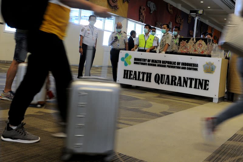 Passengers walk as they are checked by Indonesian Health Quarantine using thermal screening at the international arrival terminal of I Gusti Ngurah Rai airport in Bali