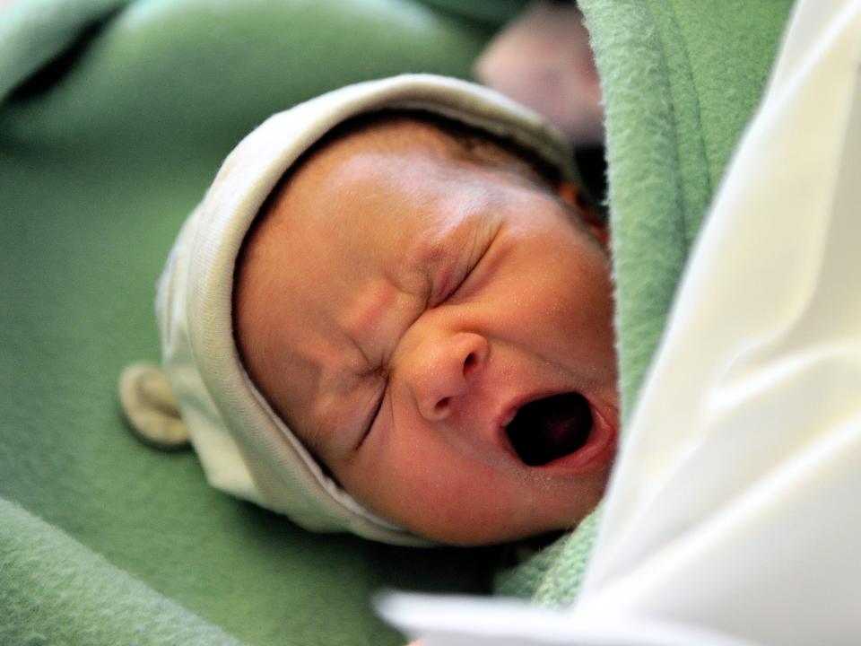 newborn baby cries while wearing a hat