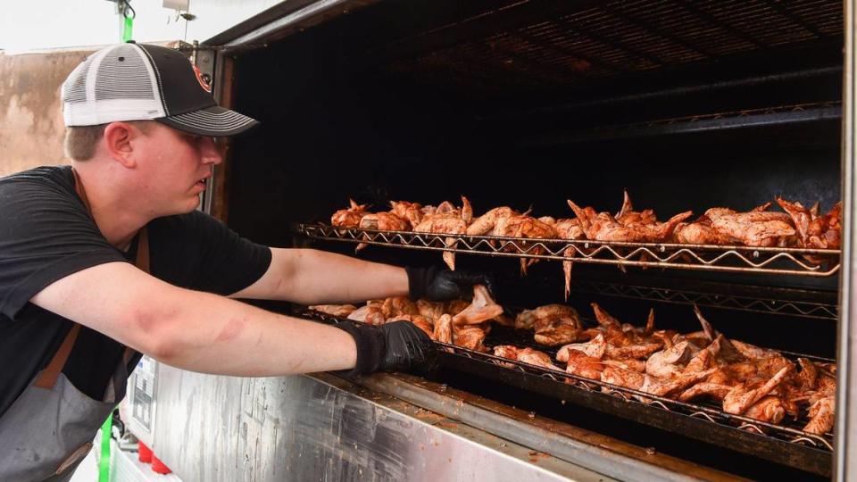 Jesse Weiser with GQue BBQ of Denver, Colo,, puts a batch of chicken in a pit. The three-day Kansas City BBQ Festival in the parking lot of the GEHA Field at Arrowhead Stadium concluded Sunday, July 11, 2021.