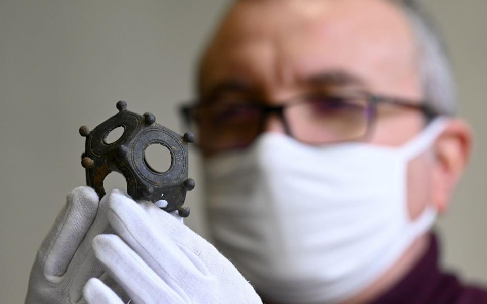 A member of the DRAC (Lorraine Regional Directorate of Cultural Affairs) inspects a Roman dodecahedron or Gallo-Roman Dodecahedron - JEAN-CHRISTOPHE VERHAEGEN /AFP