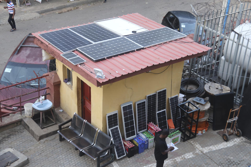 A man stands outside a shop with solar panels for sale in Abuja, Nigeria, Saturday June 17, 2023. Nigeria's removal of a subsidy that helped reduce the price of gasoline has increased costs for people already struggling with high inflation. But it also potentially accelerates progress toward reducing emissions in Africa's largest economy. (AP Photo/Olamikan Gbemiga)