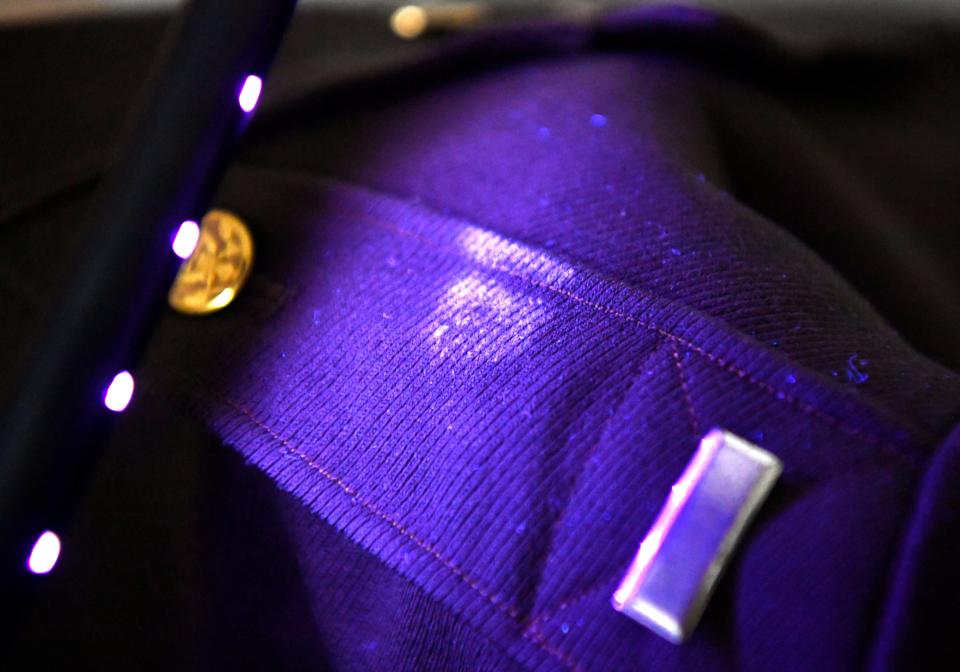 Using a handheld ultraviolet light, Mikayla Spivey, the executive director of the 12th Armored Division Memorial Museum, on Thursday illuminates mold which has been growing on one of the museum’s World War II US Army uniforms.