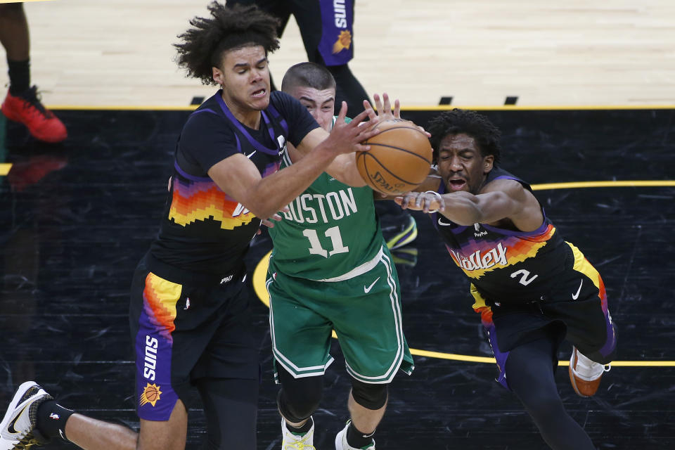 Phoenix Suns forward Cam Johnson, right, and guard Langston Galloway (2) battle for control of a loose ball with Boston Celtics guard Payton Pritchard (11) during the second half of an NBA basketball game, Sunday, Feb. 7, 2021, in Phoenix. (AP Photo/Ralph Freso)