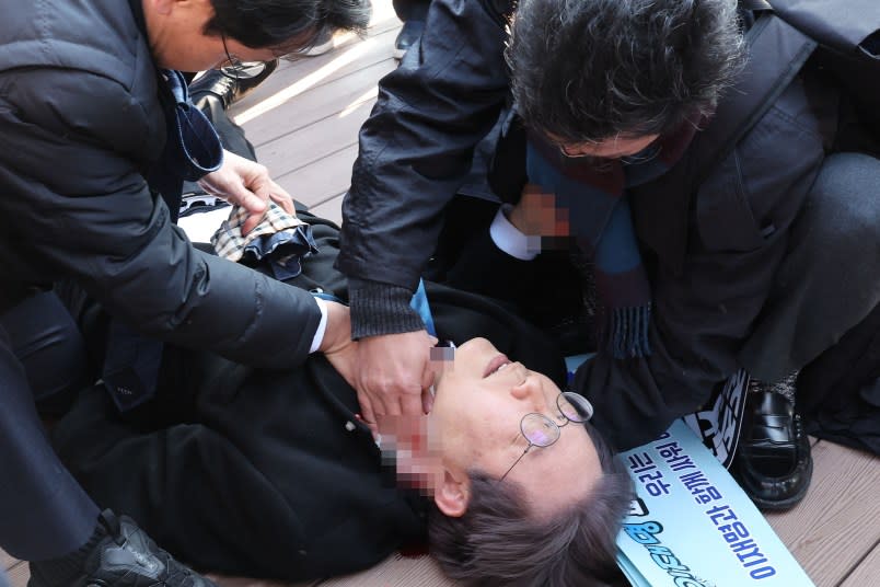 BUSAN, SOUTH KOREA – JANUARY 02: (EDITORS NOTE: The identity of people in this image has been obscured at the request of the image source; image pixelated by source) In this handout image provided by The Busan Daily News, Lee Jae-myung, leader of the main opposition Democratic Party, lies down after he was attacked by an assailant of his neck during a visit to the construction site of an airport on January 02, 2024 in Busan, South Korea. Lee, leader of the opposition Democratic Party, was stabbed in the neck by an assailant while speaking to the media in the southern city of Busan. Lee survived and is in a stable condition at a local hospital. (Photo by The Busan Daily News via Getty Images)