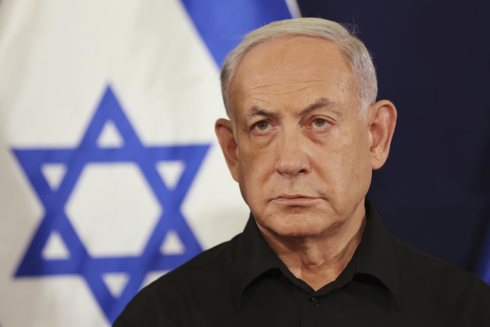 Israeli Prime Minister Benjamin Netanyahu looks on at a press conference, with the Israeli flag in the background.