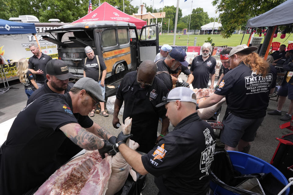 Members of The Shed BBQ and Blues Joint team season whole hogs as they compete at the World Championship Barbecue Cooking Contest, Friday, May 17, 2024, in Memphis, Tenn. (AP Photo/George Walker IV)