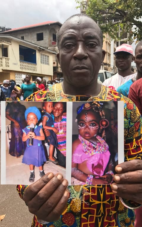 Amara Kallon, displays photos of his late daughter Hawa Kalon, who died after heavy flooding and mudslides, outside Connaught hospital morgue in Sierra Leone, Freetown, Wednesday, Aug. 16 , 2017 - Credit: AP