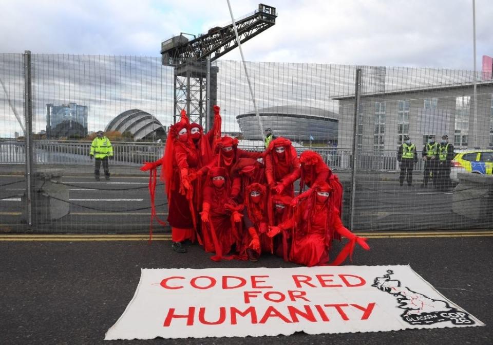 Protesters posing in front of a sign that says "Code Red For Humanity"