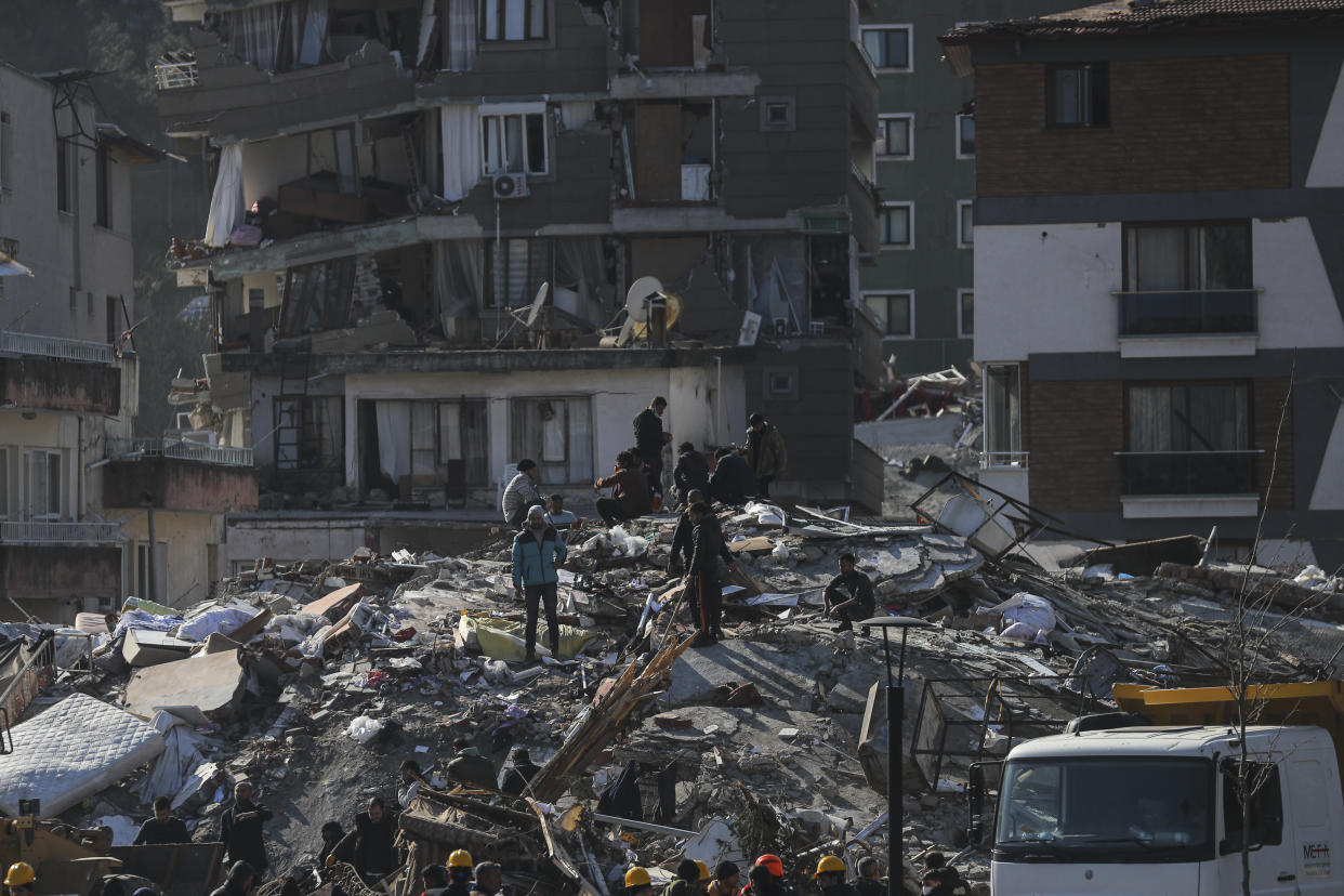 Men walk among the debris of collapsed buildings in Hatay, southern Turkey, Thursday, Feb. 9, 2023. Emergency crews made a series of dramatic rescues in Turkey on Friday, pulling several people, some almost unscathed, from the rubble, four days after a catastrophic earthquake killed more than 20,000. (AP Photo/Can Ozer)