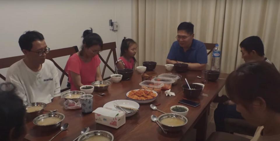 People gather around a table to eat in "Beyond Utopia."