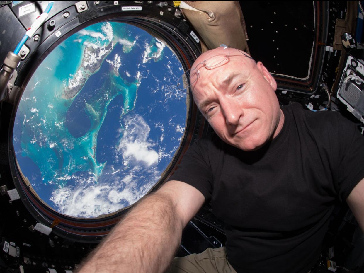 scott kelly looking at earth through the porthole of a spacecraft