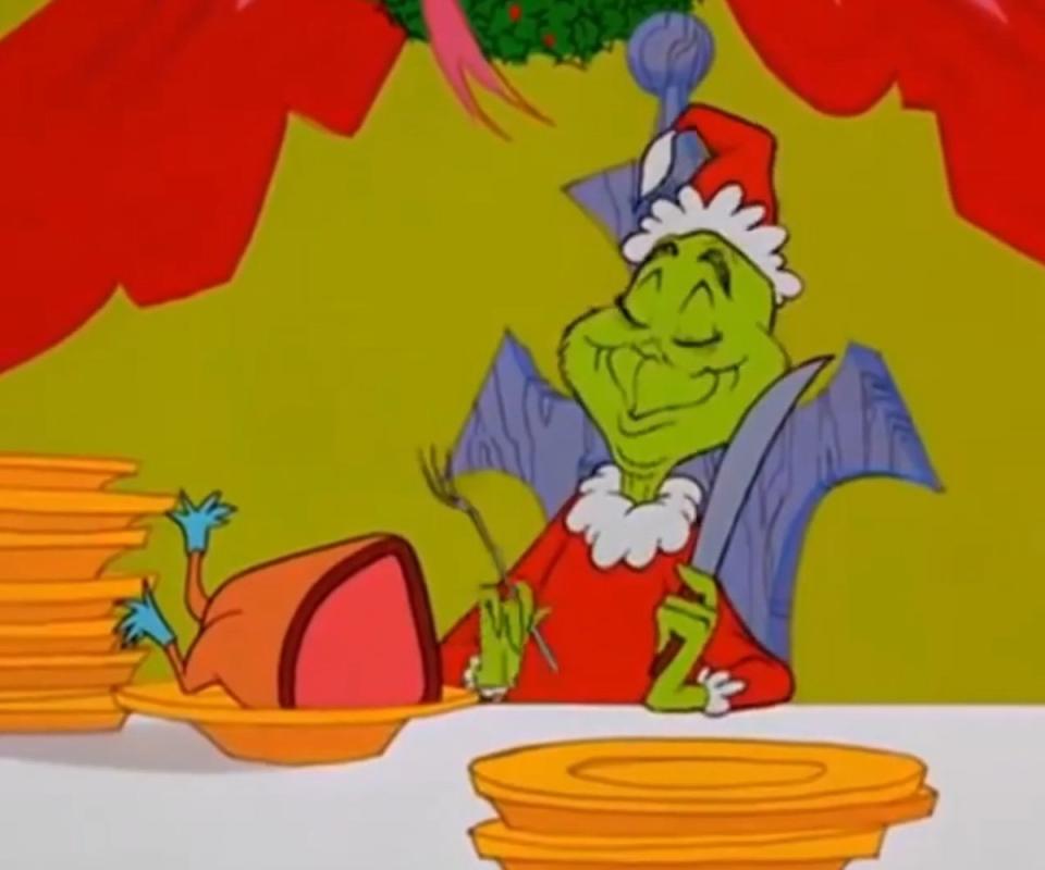 The Grinch dressed as Santa slicing up the roast beast