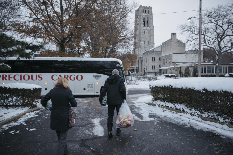 Gary Benjamin, center, brings bags full of chips and sandwiches onto the bus before departing from Saint Paul's Episcopal Church in Cleveland Heights, Ohio for Federal Court in Ann Arbor, Mich. on Nov. 28, 2018. Benjamin and his wife, Melody Hart, helped organize a group of about 30 people to travel to the court to show their support for detained asylum-seeker Ansly Damus.&nbsp;