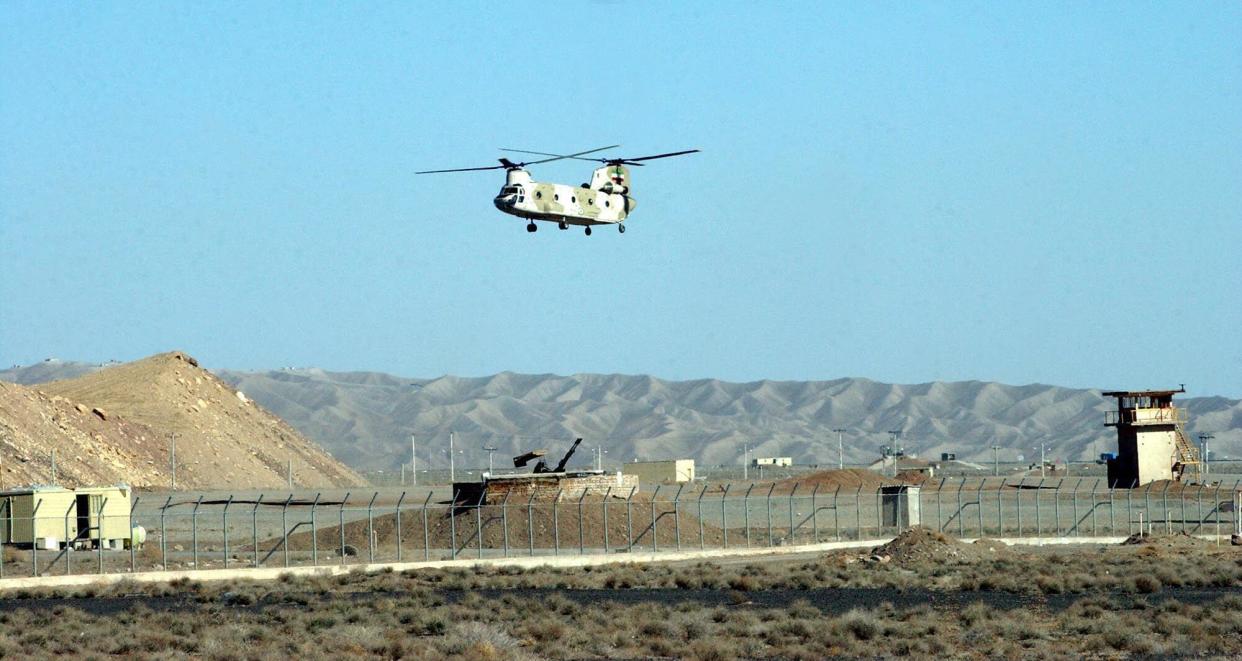 An Iranian helicopter flies over an anti-aircraft gun at the Natanz uranium enrichment facilities some 200 miles (322 km) south of the capital Tehran, Iran Wednesday March 30, 2005. The central Iranian cities of Natanz and Isfahan house the heart of Iran's nuclear program. The conversion facility in Isfahan reprocesses uranium ore concentrate, known as yellowcake, into uranium hexaflouride gas. The gas is then taken to Natanz and fed into the centrifuges for enrichment. Iran's President Mohammad Khatami is scheduled to visit the Natanz and Isfahan facilities Wednesday, with the head of Iran's 