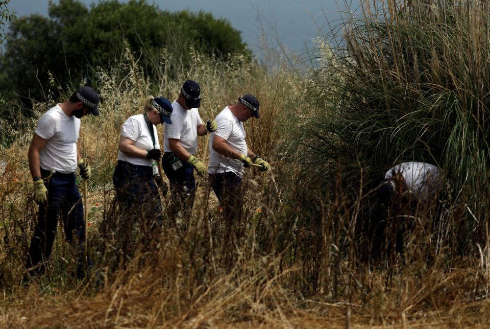 British policemen search the ground using sticks inside a cordoned-off area, in Praia da Luz, Lagos, southern Portugal, Friday, June 6, 2014. Police investigating the disappearance of Madeleine McCann continued to search a cordoned off area of scrubland near where the British girl vanished seven years ago. (AP Photo/Francisco Seco)