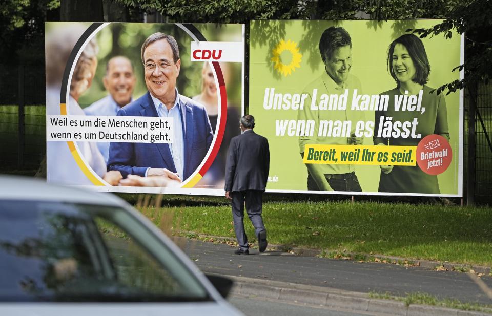 A election poster for the Green Party shows top candidate Annalena Baerbock, right, beside a poster for top candidate for the German Christian Democrats, Armin Laschet, left, at a street in Essen, Germany, Wednesday, Aug. 25, 2021. A large chunk of the German electorate remains undecided going into an election that will determine who succeeds Angela Merkel as chancellor after 16 years in power. Recent surveys show that support for German political parties has flattened out, with none forecast to receive more than a quarter of the vote. (AP Photo/Martin Meissner)