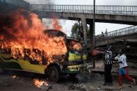 <p>Supporters of Kenyan’s opposition party National Super Alliance (NASA) throw water onto a burning bus during a demonstration on Nov. 17, 2017 in Nairobi. (Photo: Yasuyoshi Chiba/AFP/Getty Images) </p>