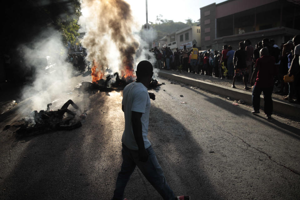 Bystanders gather around the bodies of alleged gang members that were set on fire by a mob after they were stopped by police while traveling in a vehicle in the Canape Vert area of Port-au-Prince, Haiti, Monday, April 24, 2023. (AP Photo/Odelyn Joseph)