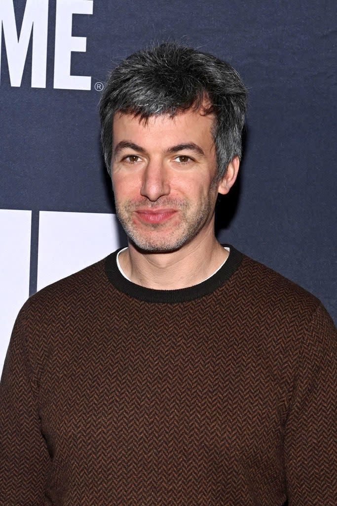 Person smiling at the camera with short hair, wearing a patterned sweater