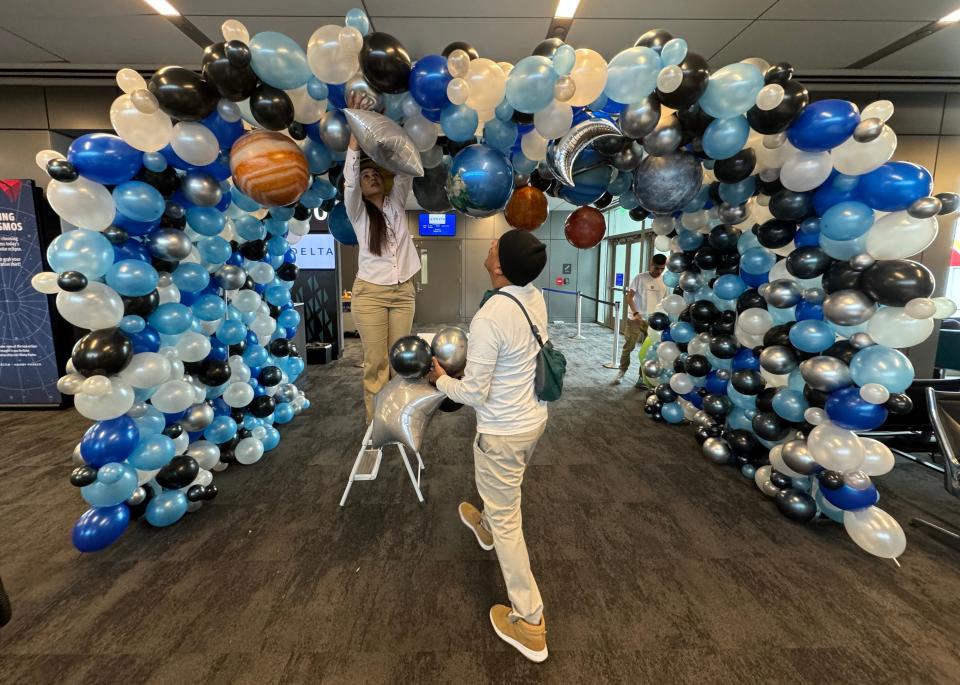 Noraida Inojosa, owner of Encantanora, a balloon and celebration company in Austin, Texas, arranges an eclipse centerpiece for passengers to go under before the 12:15p.m. flight to Detroit on Monday, April 8, 2024. 130 passengers from around the US came to Austin to take this special eclipse flight to Detroit at 35,000 feet with hopes to witness 4 minutes of totality.