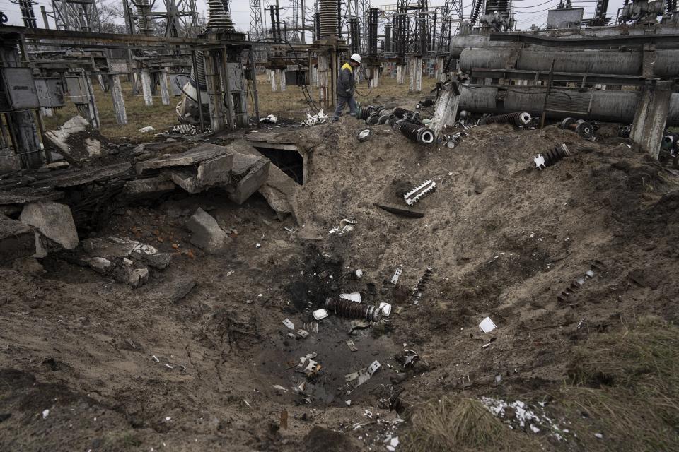 A worker at a power plant walks past a crater caused by a Russian attack in central Ukraine, Thursday, Jan. 5, 2023. When Ukraine was at peace, its energy workers were largely unheralded. War made them heroes. They're proving to be Ukraine's line of defense against repeated Russian missile and drone strikes targeting the energy grid and inflicting the misery of blackouts in winter. (AP Photo/Evgeniy Maloletka)