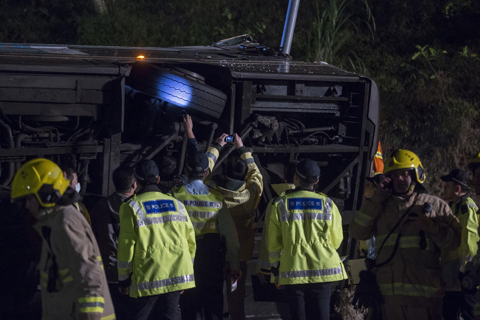 <p>Investigators inspect the underside of a bus after it crashed in Hong Kong on Feb. 10, 2018. (Photo: Isaac Lawrence/AFP/Getty Images) </p>