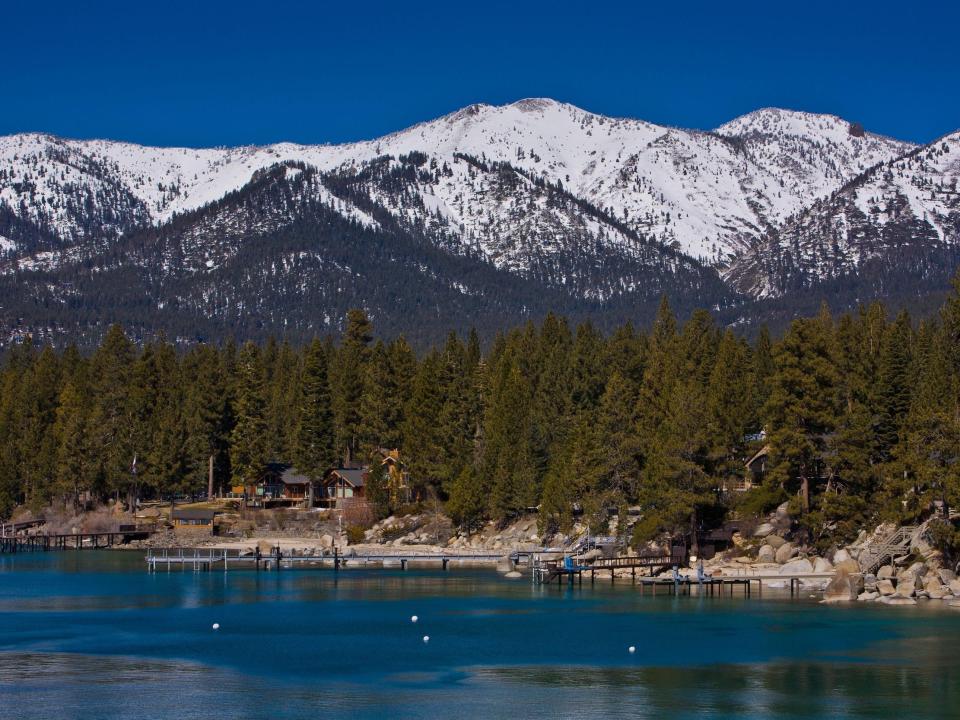 Homes and docks on the shore of Lake Tahoe with mountains and trees in the background