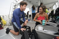 University of Miami's Rosenstiel School of Marine & Atmospheric Science senior research associates Dalton Hesley, left, and Liv Williamson prepare for a night dive to check on coral spawning, Monday, Aug. 15, 2022, in Key Biscayne, Fla. A group of students and scientists were hoping to observe the coral spawn and collect their eggs and sperm, called gametes, to take back to the lab to hopefully fertilize and create new coral that will later be transplanted to help repopulate part of the Florida Reef Tract. (AP Photo/Wilfredo Lee)