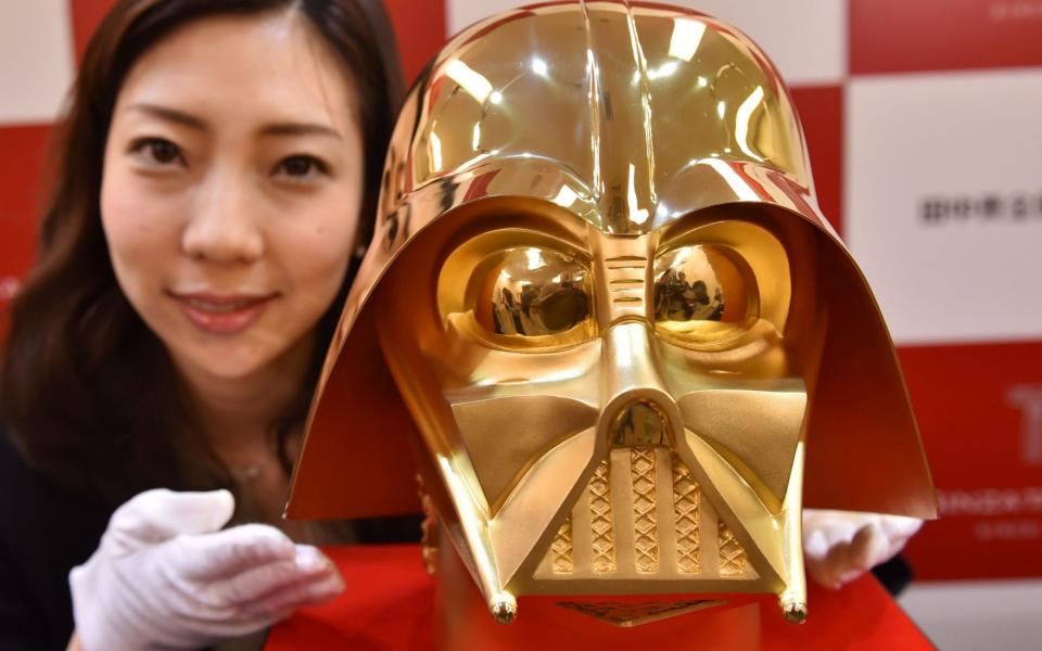 A employee of the Tokyo jewellery store displays the gold Darth Vader mask, which weighs just over 33 pounds - Credit: AFP