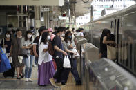 FILE - In this July 31, 2021, file photo, passengers wearing face masks to help curb the spread of the coronavirus get on board a west-bound bullet train at Tokyo Station in Tokyo. Outside the Olympic bubble, fueled by the more contagious delta variant, infections in Tokyo have logged new daily records and nearly tripled in the first week after the Games opened on July 23. Japanese officials say the surge is unrelated to the Olympics. (AP Photo/Kantaro Komiya, File)