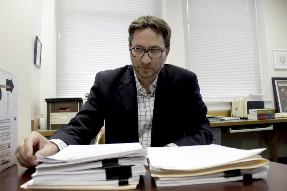 FILE - Carl Macpherson, executive director at Metropolitan Public Defender, examines the file in a double murder case that was recently pushed back for trial in his office in Portland, Ore., on May 5, 2022. (AP Photo/Gillian Flaccus, File)