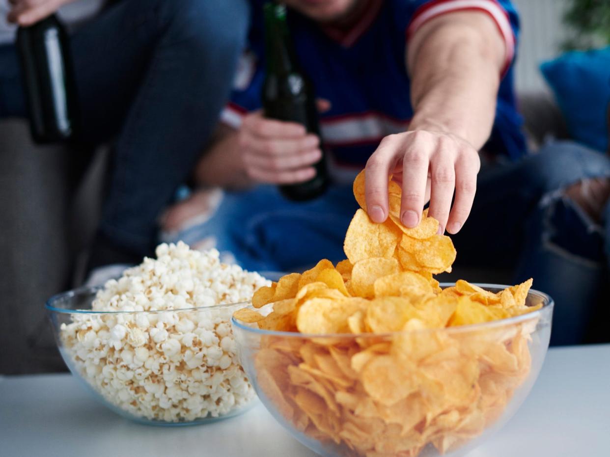 a close up of a man's hand grabbing potato chips