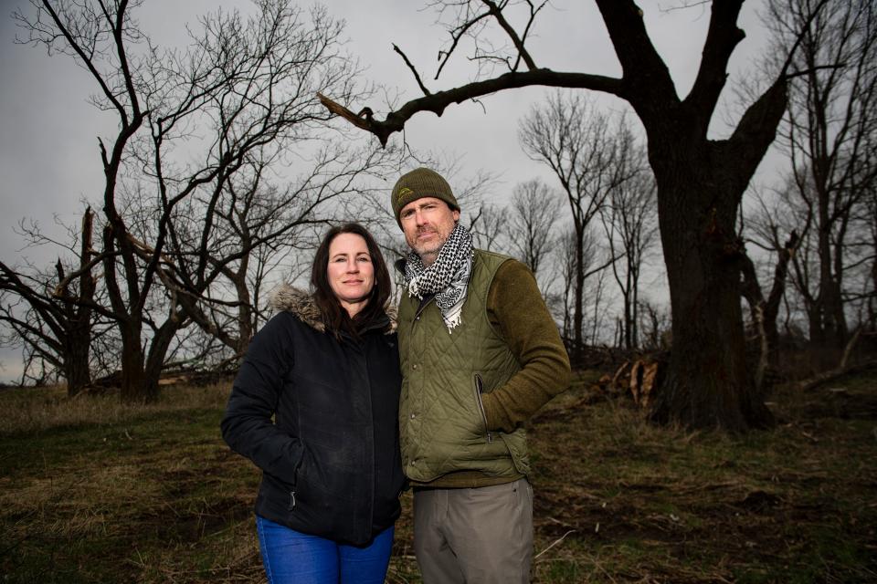 PepperHarrow Farm co-owners Jennifer and Adam O'Neal posed for a portrait near damaged trees on their property last April in Winterset.