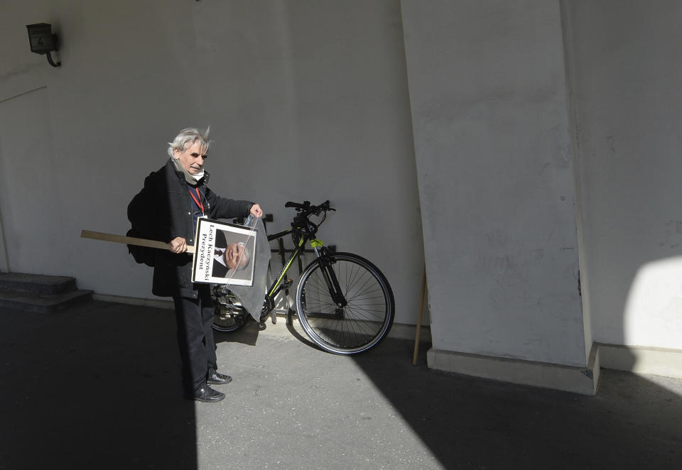 A man with a portrait of the late President Lech Kaczynski readies to go home after a scaled-down observance in memory of Kaczynski and 95 other prominent Poles who were killed in a plane crash in Russia 10 years ago, in Warsaw, Poland, on Friday, April 10, 2020. The observances were scaled down to just a few people and no crowd under social distancing regulations against the spread of the coronavirus. The new coronavirus causes mild or moderate symptoms for most people, but for some, especially older adults and people with existing health problems, it can cause more severe illness or death..(AP Photo/Czarek Sokolowski)