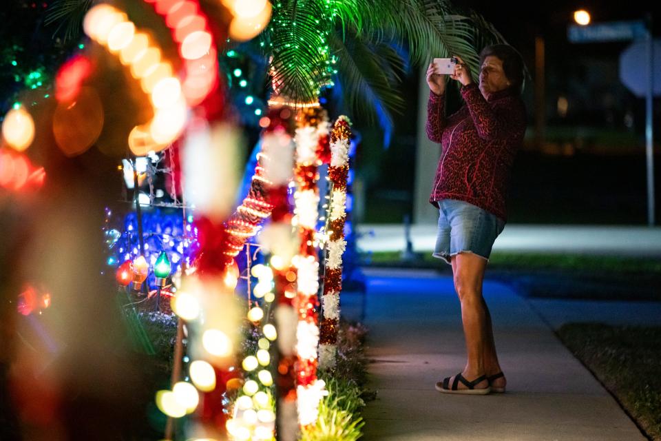 Deb Meyer of Naples takes photos of the decorations at the home of Ron Spering in Marco Island on Wednesday, Dec. 6, 2023.