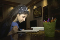 Baneen Ahmed sits at a table to read notes during the COVID-19 coronavirus lockdown in Amman, Jordan on April 15, 2020. In the future, the young refugee from Iraq sees herself studying abroad, maybe in the United States or Turkey. She’s thought about a career in medicine, but is excited by any opportunity to learn. For her, school represents hope. (AP Photo/Omar Akour)