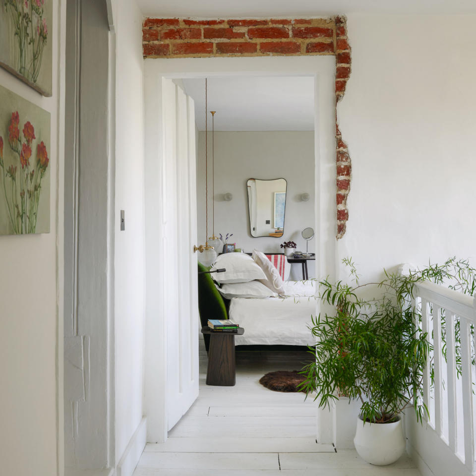 Hallway displaying view into master bedroom, houseplant and stair railing