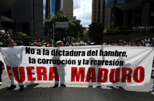 Supporters of Venezuelan opposition leader Juan Guaido hold a banner reading "Maduro Out" as they protest against President Nicolas Maduro in Caracas