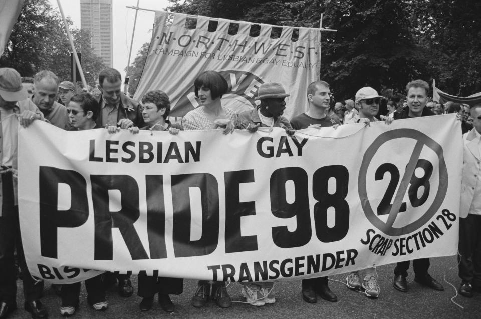 Celebrities help to hold a banner opposing Section 28, at the Lesbian, Gay, Bisexual, and Transgender Pride event, London, 4th July 1998. Those present include (from second left) actor Michael Cashman, comedian Rhona Cameron and activist Peter Tatchell. First and second from right are musician and radio presenter Tom Robinson, and comedian and TV presenter Graham Norton. Section 28 was an amendment to the Local Government Act 1988, passed by the British parliament the previous May and forbidding the 'promotion' of homosexuality by local authorities. It was repealed in 2003. (Photo by Steve Eason/Hulton Archive/Getty Images)