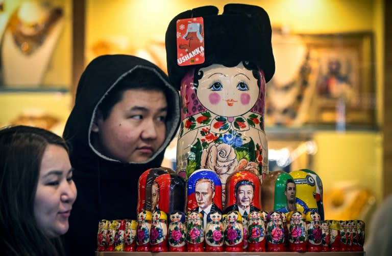 Des touristes regardent des poupées russes à l'effigie de Xi Jinping et Vladimir Poutine, à Moscou le 15 novembre 2023 (Alexander NEMENOV)