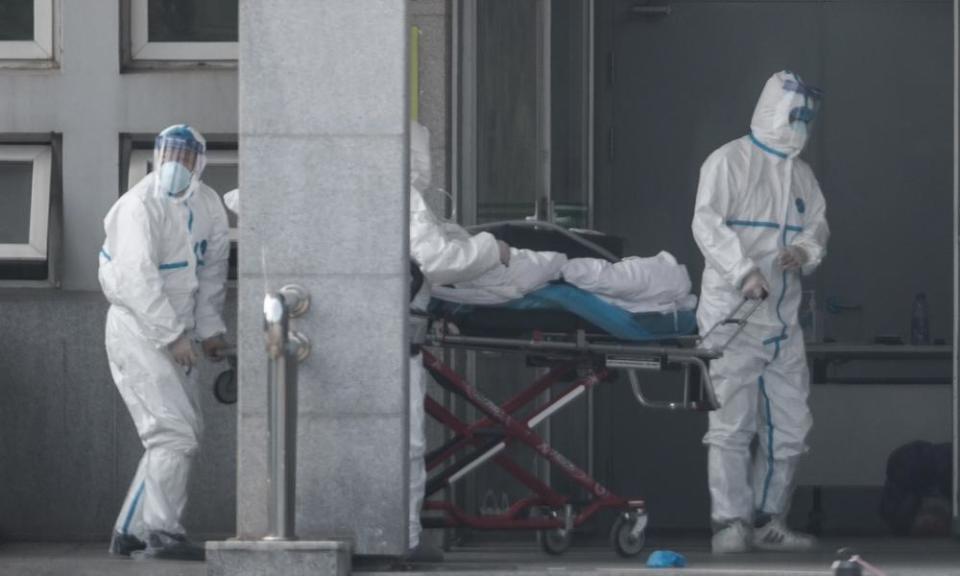 Medical staff in biohazard suits carry a patient into the Wuhan hospital where patients infected with the new strain of coronavirus are being treated.